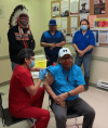 Cross Lake Coun. Mervin Garrick receives the first dose of the vaccine at the nursing station by Nurse Brenda Frogge on Thursday evening as Chief David Monias, Vice-Chief Ivan Monias and Coun. Donnie Mckay watch. (Facebook photo)