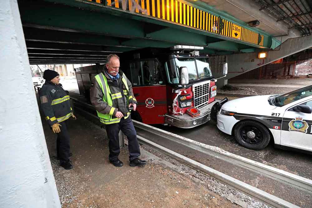 RUTH BONNEVILLE  /  WINNIPEG FREE PRESS 
Winnipeg Police Officers and Fire Crews survey the damage on a stolen fire truck that was stopped by a police vehicle under the Donald Street Bridge on Assiniboine Ave., Friday.