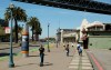 FILE - In this April 18, 2019, file photo, a man rides a scooter near children playing along the Embarcadero in San Francisco. Tired of San Francisco sidewalks being used as a testing ground for delivery robots, drones, and electric scooters, city supervisors will vote Tuesday, Dec. 10 to set up a new regulatory office that would require businesses to get permits before trying out new technology that uses public space. (AP Photo/Eric Risberg, File)