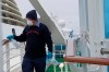 CORRECTS COAST GUARD TO NATIONAL GUARD-In this photo provided by Michele Smith, a cruise ship worker cleans a railing on the Grand Princess Thursday, March 5, 2020, off the California coast. Scrambling to keep the coronavirus at bay, officials ordered a cruise ship with about 3,500 people aboard to stay back from the California coast Thursday until passengers and crew can be tested, after a traveler from its previous voyage died of the disease and at least two others became infected. A National Guard helicopter lowered test kits onto the 951-foot (290-meter) Grand Princess by rope as the vessel lay at anchor off Northern California, and authorities said the results would be available on Friday. Princess Cruise Lines said fewer than 100 people aboard had been identified for testing. (Michele Smith via AP)