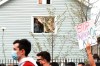 A kid looks out of a window as demonstrators attend a peace walk honoring the life of police shooting victim 13-year-old Adam Toledo, Sunday, April 18, 2021, in Chicago's Little Village neighborhood. (AP Photo/Shafkat Anowar)