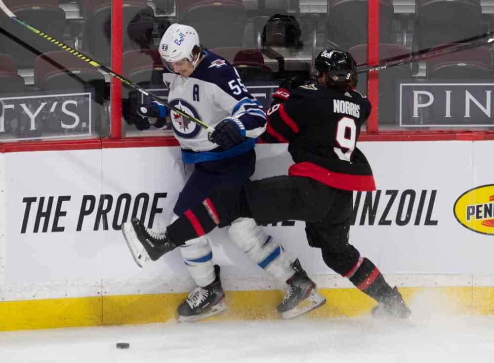 Winnipeg Jets' Mark Scheifele collides with Ottawa Senators' Josh Norris along the boards during the second period. THE CANADIAN PRESS/Adrian Wyld