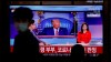 A man wearing a face mask walks near a TV screen reporting about U.S. President Donald Trump and first lady Melania Trump during a news program with a file image of Trump at the Seoul Railway Station in Seoul, South Korea, Friday, Oct. 2, 2020. Trump said early Friday that he and Melania Trump have tested positive for the coronavirus, a stunning announcement that plunges the country deeper into uncertainty just a month before the presidential election. The Korean letters read: 