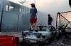 People stand on a burned up car as fires burn near a Target Store after a night of unrest and protests in the death of George Floyd early Thursday, May 28, 2020 in downtown Minneapolis. Floyd died after being restrained by Minneapolis police officers on Memorial Day. A video taken by a bystander shows a Minneapolis police officer with his knee on the neck of a man in custody who later died. The four officers involved have been fired. (David Joles/Star Tribune via AP)