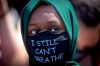 A person wears a mask Sunday, May 31, 2020, with a message at the Minneapolis corner where George Floyd was restrained by Minneapolis police. Floyd died May 25 after he was pinned at the neck by a Minneapolis police officer. (Elizabeth Flores/Star Tribune via AP)