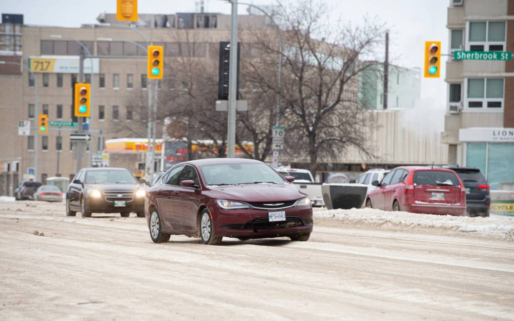 Drivers make their way over the tall ruts of snow and ice as they switch lanes while going eastbound down Portage Avenue on Tuesday. (Mike Sudoma / Winnipeg Free Press)