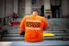 A person wearing an orange shirt honouring residential school survivors bows their head as they listen to a speaker at the ProtectEdMB rally at the Manitoba legislature, Saturday morning.  (Daniel Crump / Winnipeg Free Press)