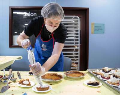 JESSICA LEE / WINNIPEG FREE PRESS
Dallas Holden, a staff member, adds whipped cream to plates of pie at Siloam Mission on Friday when the organization fed dozens of community members Thanksgiving lunch.