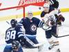 Jets goalie Connor Hellebuyck and the Oilers’ Zach Hyman eye a loose puck in front of the Winnipeg net Saturday during second-period action in Winnipeg. (John Woods / The Canadian Press)