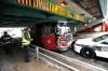 Police officers and fire crews survey the damage on a stolen fire truck that was stopped by a police vehicle under the Donald Street Bridge on Assiniboine Avenue Friday. (Ruth Bonneville / Winnipeg Free Press files)