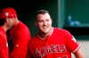 FILE - In this April 15, 2019, file photo, Los Angeles Angels designated hitter Mike Trout smiles in the dugout after he scored on a home run by Brian Goodwin against the Texas Rangers during the first inning of a baseball game in Arlington, Texas. If Major League Baseball and the players' union can partially save its 2020 season, the potential 60-to 70-game season would be much shorter than the usual 162-game grind. It would look much more like a college baseball season. “If there's 60 games on the schedule, someone like Mike Trout is going to play 60 games,” former major league baseball player and college coach Tracy Woodson said. (AP Photo/Michael Ainsworth, File)