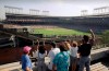 FILE - In this Monday, July 9, 1990, file photo, spectators watch an All-Star Game practice session from the roof of a building just outside Chicago's Wrigley Field. This week, Major League Baseball players and owners reached an agreement to play an abbreviated, 60-game season that would start July 23 or 24 in teams’ home ballparks. But the seats will be empty. Instead, fans hoping to see a game in person will be have to settle for pressing their faces up against hotel windows, squinting through metal grates or climb to rooftops when baseball returns this month in otherwise empty stadiums. (AP Photo/Seth Perlman, File)