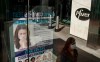 An ad for COVID-19 testing reflects on glass at a bus stop, as pedestrians walk past Pfizer world headquarters in New York on Monday Nov. 9, 2020. Pfizer says an early peek at its vaccine data suggests the shots may be 90% effective at preventing COVID-19, but it doesn't mean a vaccine is imminent. (AP Photo/Bebeto Matthews)