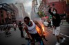 Protesters march down the street as trash burns in the background during a solidarity rally for George Floyd, Saturday, May 30, 2020, in New York. Protests were held throughout the city over the death of George Floyd, a black man who died after being restrained by Minneapolis police officers on May 25. (AP Photo/Wong Maye-E)