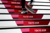 A commuter walks down stairs leading to a subway station before the start of the 2020 Summer Olympics, Wednesday, July 21, 2021, in Tokyo. (AP Photo/Jeff Roberson)