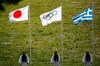 FILE - In this Thursday, March 12, 2020, file photo, Greek Evzones guards stand next to Japan, Olympic and Greece flags, from left, during the flame lighting ceremony at the closed Ancient Olympia site, birthplace of the ancient Olympics in southern Greece. U.S. President Donald Trump's suggestion to postpone the Tokyo Olympics for a year because of the spreading virus was immediately shot down by Japan's Olympic Minister Seiko Hashimoto. (AP Photo/Yorgos Karahalis, File)