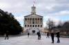 People walk across the quiet Legislative Plaza in front of the State Capitol Sunday, Jan. 17, 2021, in Nashville, Tenn. The FBI warned of the potential for armed protests at the nation's Capitol and all 50 state capitol buildings beginning this weekend. (AP Photo/Mark Humphrey)