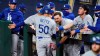 Los Angeles Dodgers' Mookie Betts (50) is congratulated after scoring on a throwing error by San Diego Padres' Fernando Tatis Jr. during the third inning in Game 3 of a baseball National League Division Series Thursday, Oct. 8, 2020, in Arlington, Texas. (AP Photo/Tony Gutierrez)