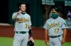 Oakland Athletics' Jonah Heim (37) gestures to the dugout after hitting a single off of Texas Rangers starting pitcher Kyle Gibson as first base coach Mike Aldrete, right, stands by in the seventh inning of a baseball game in Arlington, Texas, Tuesday, Aug. 25, 2020. The single was Heim's first major league hit. (AP Photo/Tony Gutierrez)