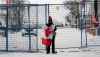 A lone protester stands draped in the Canadian flag at a temporary fence controlling access to streets near Parliament, in Ottawa, Sunday, Feb. 20, 2022. THE CANADIAN PRESS/Adrian Wyld