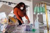 Adilisha Patrom, owner of a co-working and event space next to Gallaudet University, organizes face masks, hand sanitizer and other supplies inside her pop up shop on Thursday, March 5, 2020, in Washington. Inside her storefront, she displays different face mask models and hand sanitizer bottles alongside information from the Centers for Disease Control and Prevention. (AP Photo/Nathan Ellgren)