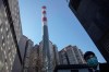 In this photo taken Saturday, Feb. 22, 2020, a security guard looks out near a smoke stack near residential apartments in Beijing, China. Regulators on Monday promised tax cuts and other aid to help companies recover from China's virus outbreak and expressed confidence the ruling Communist Party's growth targets can be achieved despite anti-disease controls that shut down much of the economy. (AP Photo/Ng Han Guan)