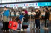 Travelers wearing face masks line up near the Japan Airlines check-in counters at Beijing Capital International Airport in Beijing, Thursday, Jan. 30, 2020. China counted 170 deaths from a new virus Thursday and more countries reported infections, including some spread locally, as foreign evacuees from China's worst-hit region returned home to medical observation and even isolation. (AP Photo/Mark Schiefelbein)