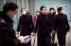 Flight crew members wearing face masks walk through the international arrivals area at Beijing Capital International Airport in Beijing, Thursday, Jan. 30, 2020. China counted 170 deaths from a new virus Thursday and more countries reported infections, including some spread locally, as foreign evacuees from China's worst-hit region returned home to medical observation and even isolation. (AP Photo/Mark Schiefelbein)