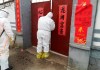 In this Saturday, Feb. 1, 2020, photo, government workers in protective suits visit a family under home quarantine in Zouping in eastern China's Shandong Province. The sing on the right reads: 