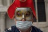 A Russian tourist dons both a carnival mask and a protective face mask as he visits St. Mark's square Venice, Italy, Tuesday, Feb. 25, 2020. Italy has been scrambling to check the spread of Europe's first major outbreak of the new viral disease amid rapidly rising numbers of infections and calling off the popular Venice Carnival and closing tourist attractions. (AP Photo/Renata Brito)