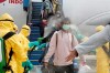 In this photo released by the Indonesian Foreign Ministry, Indonesians who arrived from Wuhan, China, are sprayed with antiseptic at Hang Nadim Airport in Batam, Indonesia Sunday, Feb. 2, 2020. Indonesians evacuated from Wuhan, the Chinese city at the center of a deadly virus outbreak, were transported to a quarantine zone on a remote island at the edge of the South China Sea, shortly after landing on Batam, an island near Singapore on Sunday morning. (Indonesian Foreign Ministry via AP)