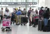 People wait in line to check in at Pearson International Airport in Toronto on Thursday, May 12, 2022.Transport Minister Omar Alghabra says the federal government is working on new measures to help ease the issues at major airports, adding that a 