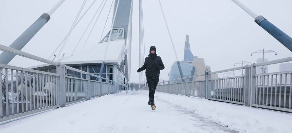 Avid runner, Blair Kroeker, makes his way across the Esplanade Riel pedestrian bridge amidst blowing snow. (Ruth Bonneville / Winnipeg Free Press)