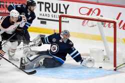 Connor Hellebuyck is scored on by Connor McDavid, not shown, during the first period. (Fred Greenslade / The Canadian Press)