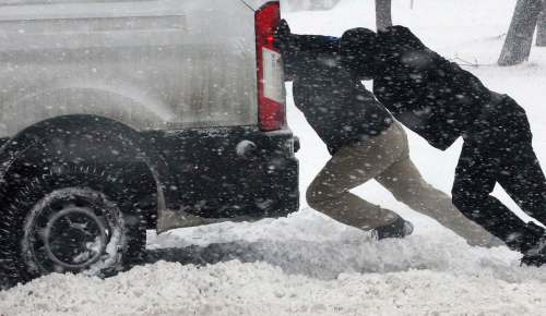 Cameron Batista (front) and others help push a delivery van stuck on Ellice Avenue on Dec. 6, 2016. (Joe Bryksa / Winnipeg Free Press files)