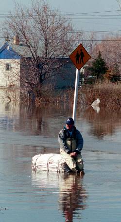 Manitoba Hydro worker Dave Crowe sits on piles of empty sand bags in Ste. Agathe. He and a few other essential workers were the only ones allowed to return after the town was evacuated. (Joe Bryksa / Winnipeg Free Press files)