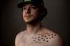 Tyler Smith’s tattoo features 16 birds, including one with a pink tail in memory of Dayna Brons, the only woman on the bus that day. (Jason Franson / The Canadian Press)