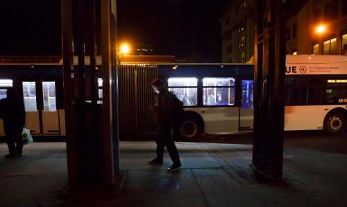 People wait for their bus to arrive at the Graham Avenue bus stop in downtown Winnipeg just after midnight Wednesday. (Mike Deal / Winnipeg Free Press)