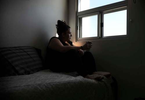 Krystle sits on her bed in her room at a women's shelter on Wednesday. (Ruth Bonneville / Winnipeg Free Press)