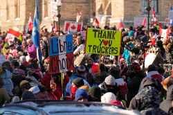 Protesters hold signs thanking truckers and promoting freedom of choice on Parliament Hill. (Adrian Wyld / The Canadian Press)