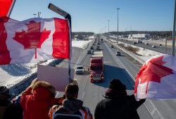 CP
Supporters wave flags on an overpass in Kanata, Ont., as a trucker convoy making it