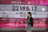 A woman wearing a face mask walks past a bank's electronic board showing the Hong Kong share index in Hong Kong, Monday, June 27, 2022. Asian shares advanced Monday after Wall Street ended a rare winning week, capped by a 3.1% gain on Friday for the benchmark S&P 500. U.S. futures and oil prices also were higher. (AP Photo/Kin Cheung)