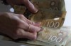 Canadian $100 bills are counted in Toronto, Feb. 2, 2016. New research paints a sombre outlook for Canadian household finances as inflation takes a bite out of real wages and rising interest rates mute economic growth. THE CANADIAN PRESS/Graeme Roy