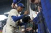 Seattle Mariners center fielder Julio Rodriguez signs autographs for fans before a baseball game against the Oakland Athletics, Sunday, July 3, 2022, in Seattle. (AP Photo/Ted S. Warren)