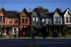 A person walks by a row of houses in Toronto on Tuesday July 12, 2022. The Bank of Canada increased its key interest rate by one percentage point Wednesday in the largest hike the country has seen in 24 years.THE CANADIAN PRESS/Cole Burston