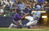 Colorado Rockies catcher Elias Diaz (35) tags out Milwaukee Brewers' Andrew McCutchen (24) during the sixth inning of a baseball game Friday, July 22, 2022, in Milwaukee. (AP Photo/Jeffrey Phelps)