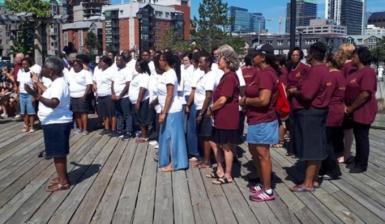 Karen Burke (left), director of Toronto Mass Choir, and singers from the Nova Scotia Mass Choir and the Toronto Mass Choir on the Halifax waterfront. (Alex Cooke / The Canadian Press)