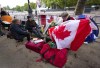 Bernadette Christie, of Grand Prairie, Alta., looks for a Canadian pin on a flag at the gates of Buckingham Palace in London, Friday, Sept. 16, 2022. For some Canadians, Queen Elizabeth's funeral today will evoke a range of emotions while for others it is a distant event that they are likely to miss. THE CANADIAN PRESS/Nathan Denette