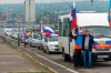 Two men pose for a photo in front of motorcade organized to support voting in a referendum in Luhansk, eastern Ukraine, Friday, Sept. 23, 2022. Voting began Friday in four Moscow-held regions of Ukraine on referendums to become part of Russia. (AP Photo)