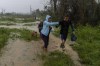 A family walks through the rain in search of shelter after their home flooded when Hurricane Ian hit in Pinar del Rio, Cuba, Tuesday, Sept. 27, 2022. Ian made landfall at 4:30 a.m. EDT Tuesday in Cuba’s Pinar del Rio province, where officials set up shelters, evacuated people, rushed in emergency personnel and took steps to protect crops in the nation’s main tobacco-growing region. (AP Photo/Ramon Espinosa)